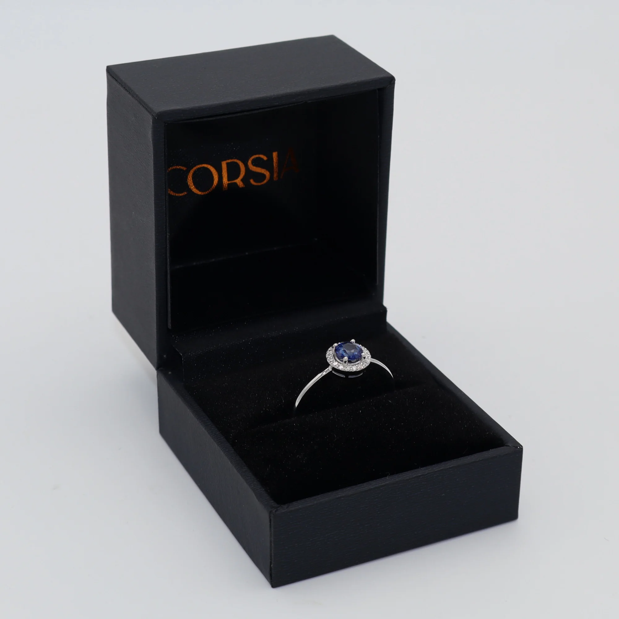 Anillo de compromiso con zafiro redondo y orla de diamantes oro blanco corsia